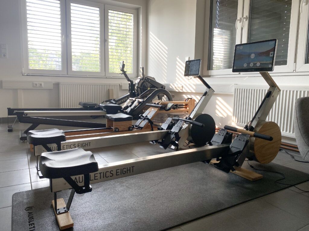 In front two Augletics rowing machines: the Augletics Eight Style and the Augletics Eight Sport. Behind them, various other rowing machines with different braking systems: water-braked, air-braked and more