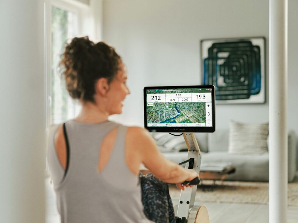 Woman training on a rowing machine with interactive display in a modern living room