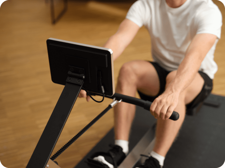 Die richtige Atmung beim Rudertraining - So funktioniert's 2 Person in Sportkleidung nutzt ein Rudergerät mit integriertem Bildschirm für ein intensives Workout.