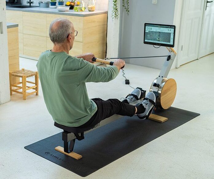 Consommation de calories en aviron : Un entraînement efficace pour atteindre vos objectifs 1 Un homme âgé utilise le rameur Augletics dans une maison moderne pour un entraînement à domicile confortable et efficace.